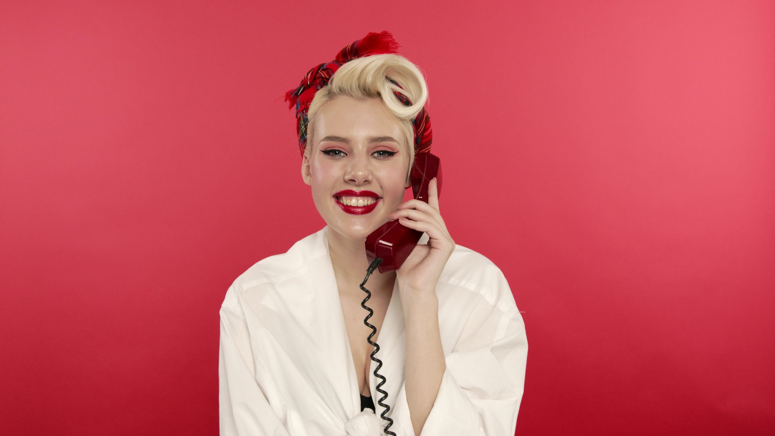 happy-pin-up-woman-smiling-and-talking-on-retro-telephone-SBI-351107592